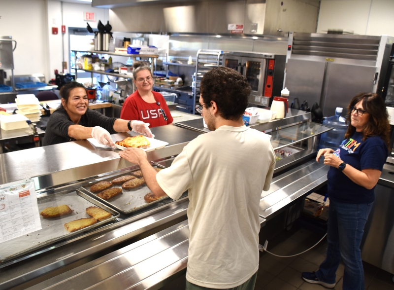 Food Service Director Holly Peters-Heady serves a meal to a student in the RA cafeteria.