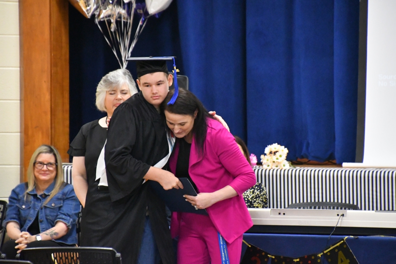 Skyler Kelly-Palmer hugs Principal Melissa Murphy as she hands him his certificate.