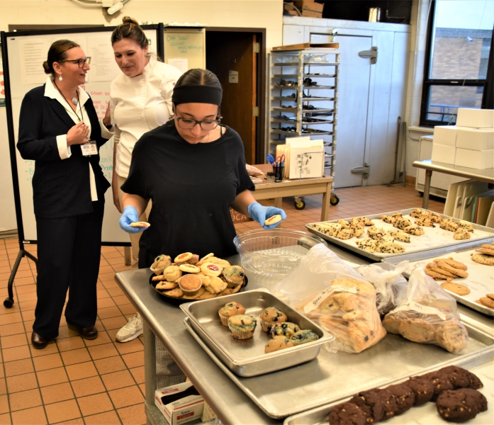 A student prepares a tray of cookies for the public.