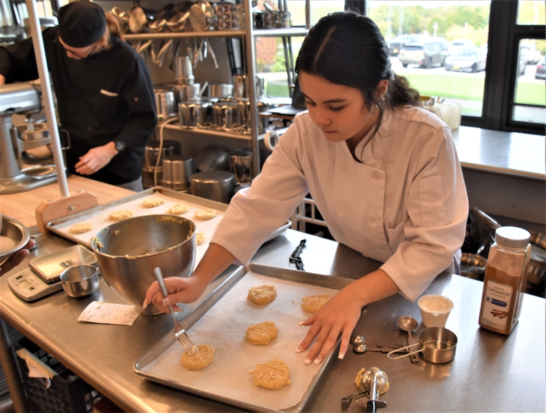 A student decorates peanut butter cookies.