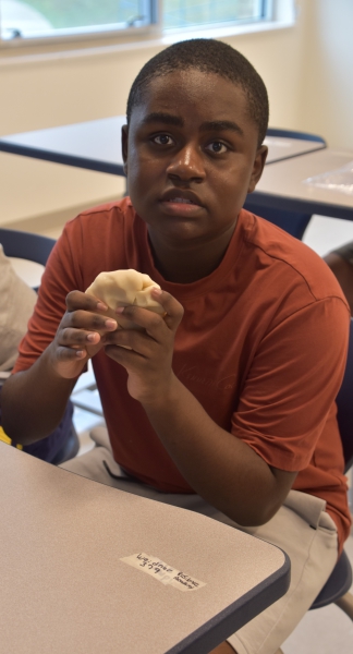 An ESY student kneads clay during an activity.