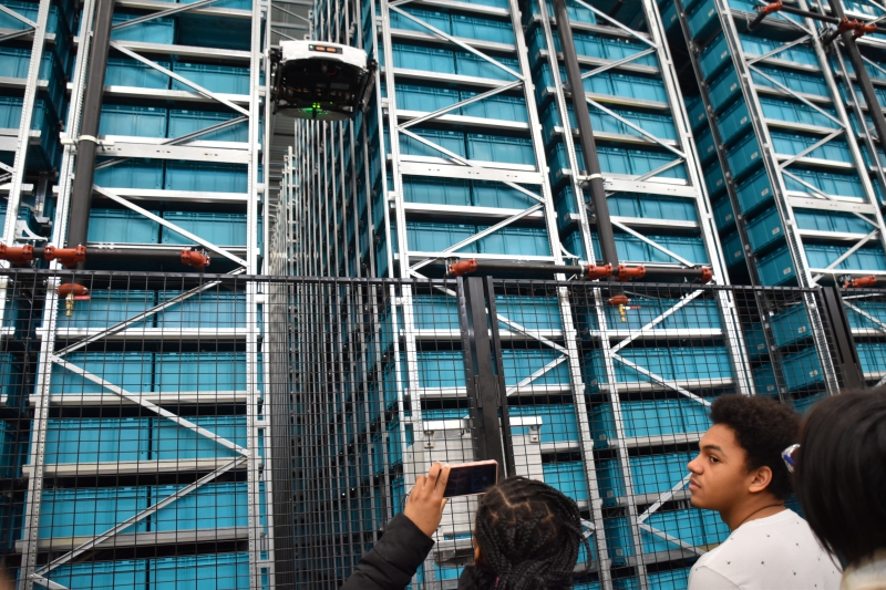 Dutchess BOCES P-TECH students look up at an autonomous robot at the Gap warehouse in Fishkill.