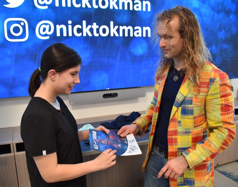 Nick Tokman presents a student with a signed poster during the presentation