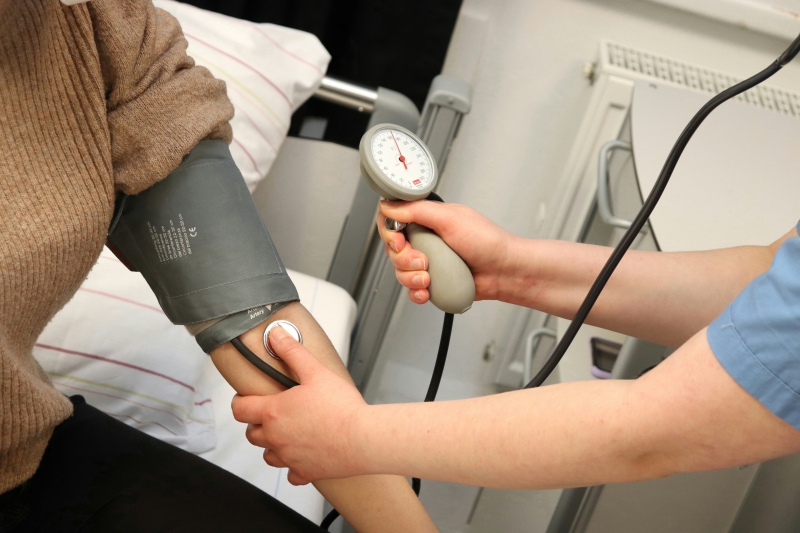 A certified nursing assistant checks a patient's blood pressure