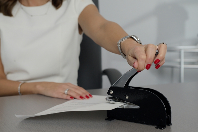 A notary places a seal on paper