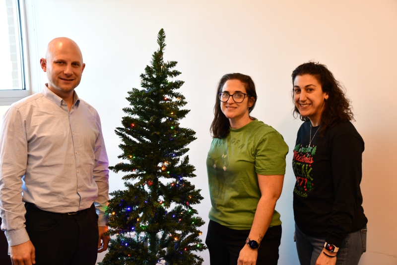 Rob LaColla, Christina Olson and Krystine Nardozzi, members of the Resilience Academy’s PBIS program, stand with one of the two trees in the conference that no longer have gift tags for staff to purchase gifts for students and their families in need.