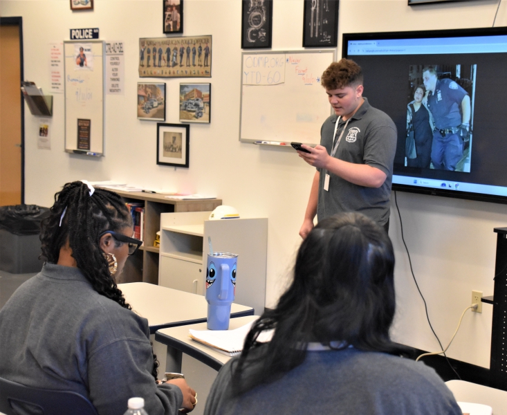 A student presents information on the first responder whose name tag and photo he wore for the ceremony.