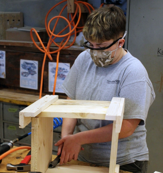 A student removes a piece of metal from the planter.