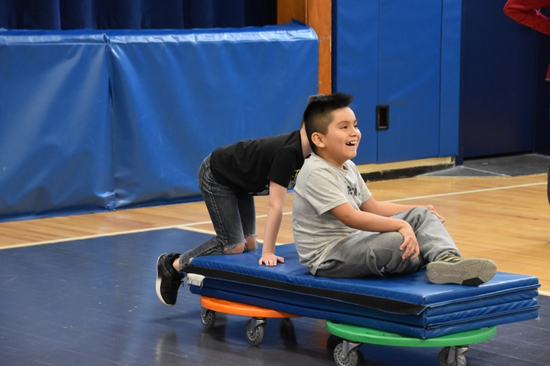One student pushes another in Salt Point Center's gym as they recreate the Winter Olympics bobsled races.